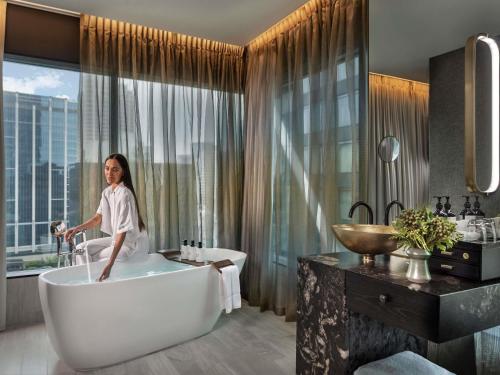 a woman sitting in a bath tub in a bathroom at SO/ Auckland in Auckland
