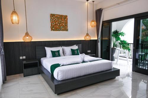a bedroom with a large white bed with green pillows at Sampai Villa Jumpa in Balong