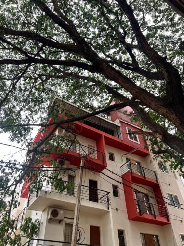 a tall red and white building with a tree at NEC Suites in Bengaluru