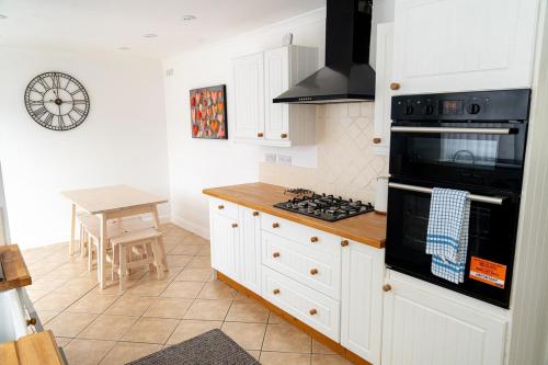 a kitchen with white cabinets and a stove top oven at Relaxing 3-Bed Family Stay in Basingstoke in Worting