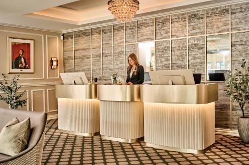a woman sitting at a table in a hotel lobby at Fru Haugans Hotel in Mosjøen