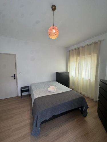 een slaapkamer met een bed en een hanglamp bij Apartamento Central Rainha in Caldas da Rainha