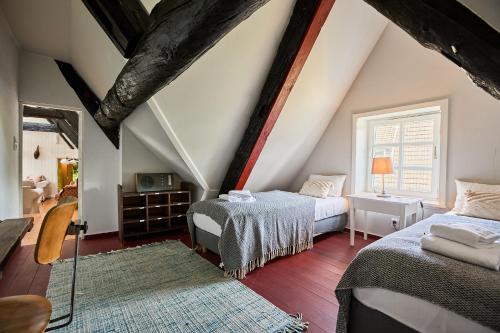 a attic bedroom with two beds and a window at Altes Fährhaus - Ferienwohnung Unnern, 170 qm in Wewelsfleth