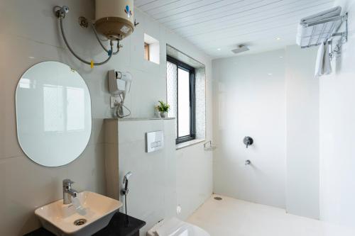 a white bathroom with a sink and a mirror at Sasa resort Udaipur in Udaipur