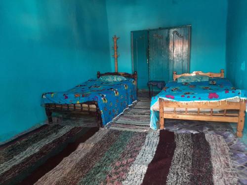 a room with two beds and a blue wall at Arman House in Aswan