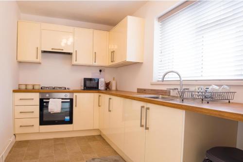 a kitchen with white cabinets and a sink and a window at House Sleeps 6 - Parking Garden Family&Contractors in Walsall