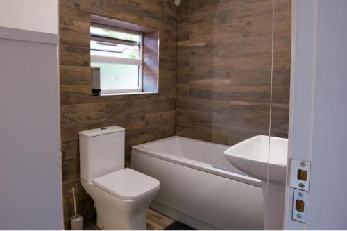 a bathroom with a toilet and a tub and a sink at House Sleeps 6 - Parking Garden Family&Contractors in Walsall