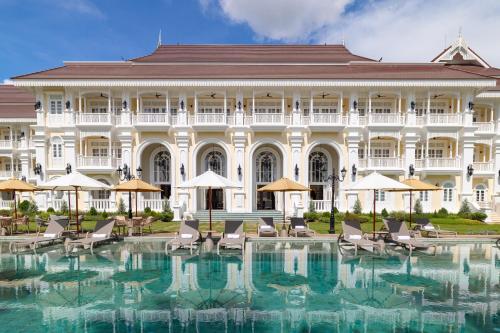 a large building with a swimming pool in front of it at Ping Pura Riverside Resort & Spa Chiang Mai in Chiang Mai