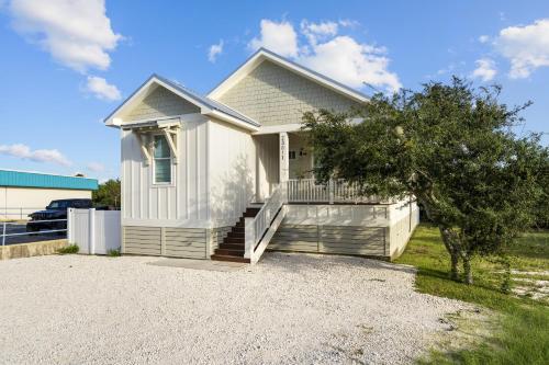 a white house with a porch and a driveway at Luxury 4BR, Across street from beach, Sleeps 10! in Gulf Shores