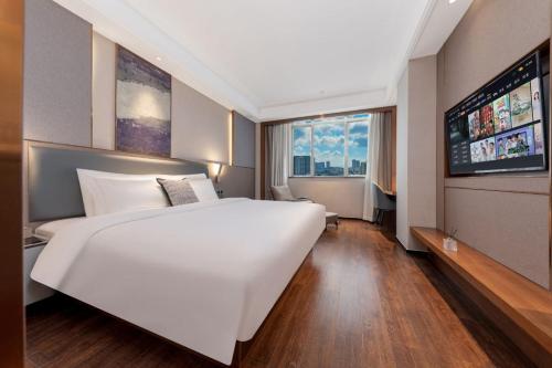 a large white bed in a room with a large window at 丘奈ChillNow酒店设计之都鹤龙地铁站店 in Guangzhou