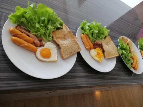 three plates of food with egg sandwiches and lettuce at The Salin Seaview Villas in Kata Beach