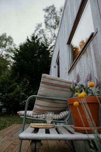 a chair on a porch with a table and a flower pot at Tiny House Alba - ervaar tiny house living in Diessen