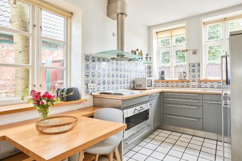 a kitchen with a wooden table and some windows at Altes Fährhaus - Ferienwohnung Unnern, 170 qm in Wewelsfleth