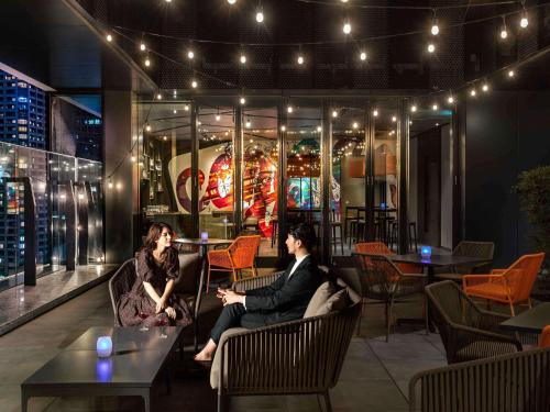 two people sitting in chairs in a restaurant at night at Pullman Tokyo Tamachi in Tokyo