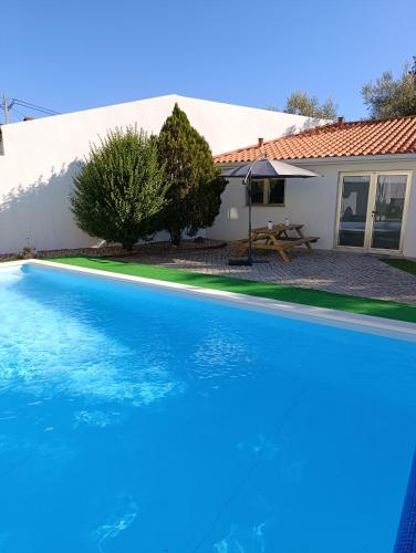 a large blue swimming pool in front of a house at Quintal do Olival- Um refúgio na Natureza in Lousã