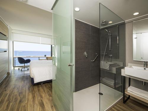 a bathroom with a shower and a bed and a sink at Pullman Vina del Mar San Martin in Viña del Mar