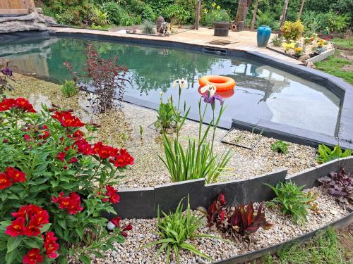 a pool of water with flowers in a garden at Gîte de la croix in La Croix-Helléan