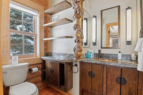 a bathroom with a toilet and a sink and a mirror at RMR: Teton View Cabin Home in WilsonWY in Wilson
