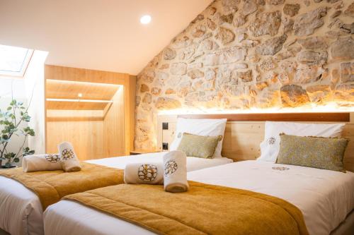 two beds in a bedroom with a stone wall at versão b in Ancião