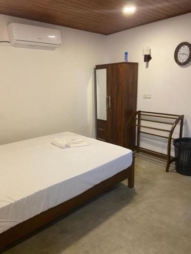 a bedroom with a bed and a clock on the wall at The Flora in Ahangama