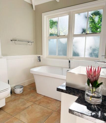 a bathroom with a tub and a toilet and windows at Clementine Cottage in Citrusdal