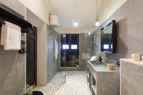 a bathroom with a walk in shower and a sink at Viraam Estate by RÊVE in Assagao