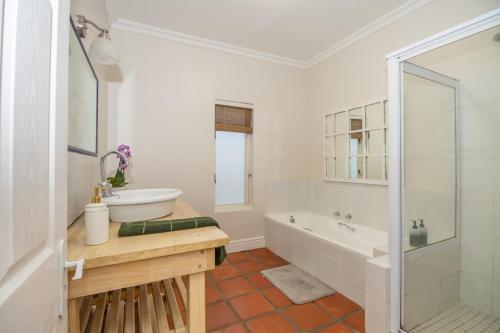 un bagno bianco con vasca e lavandino di Bloom Garden Cottage a Constantia