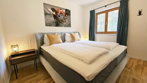 a bedroom with a bed with a cow picture on the wall at Almrose Zauber by Alpenchalet Almrose in Oberau
