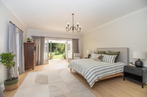 una camera da letto bianca con un letto e un lampadario di Bloom Garden Cottage a Constantia