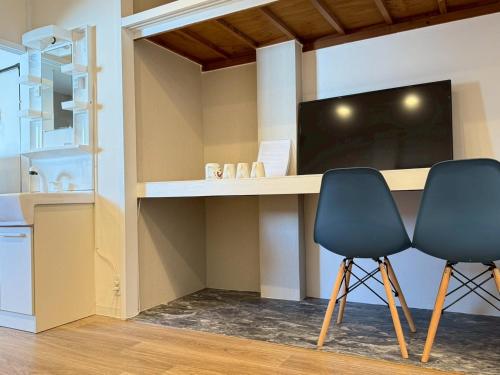 two chairs in front of a desk with a tv at Maison Grand Kishinosato in Osaka