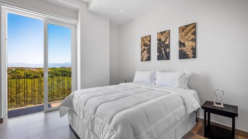 een witte slaapkamer met een groot bed en een groot raam bij Equipped 3BR House - Pool - Gym - 5 min to Beach in Nuevo Vallarta 