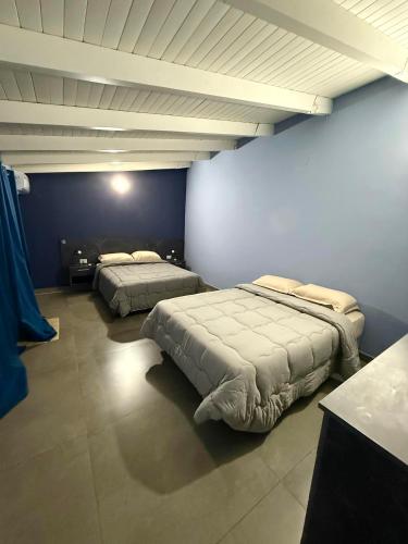 two beds in a room with blue walls at Hotel SMA in Puerto Iguazú