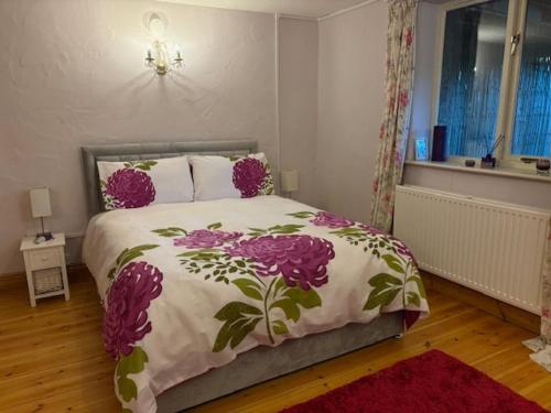 a bedroom with a bed with purple flowers on it at Olli's Summer House - Natural Pool & Jacuzzi optional in Bristol
