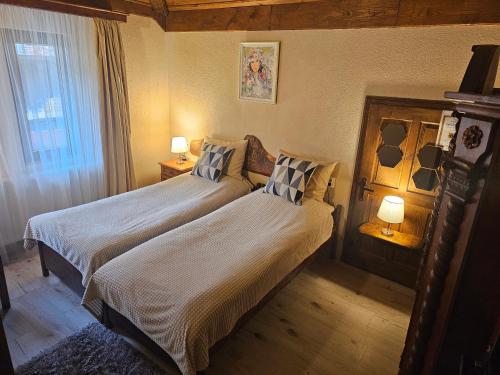 a bedroom with two beds and two lamps and a window at Къща за гости Костовският хан in Chepelare