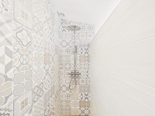 a bathroom with a shower with a tiled wall at 300m plage - maison pour 7 avec grande terrasse in Penmarcʼh