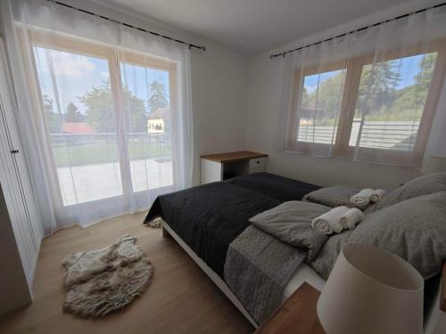 a bedroom with a bed and two large windows at Dióliget Apartman in Orfű