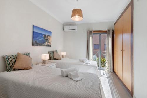a white bedroom with two beds and a window at Do Vale Hollidays in Galé