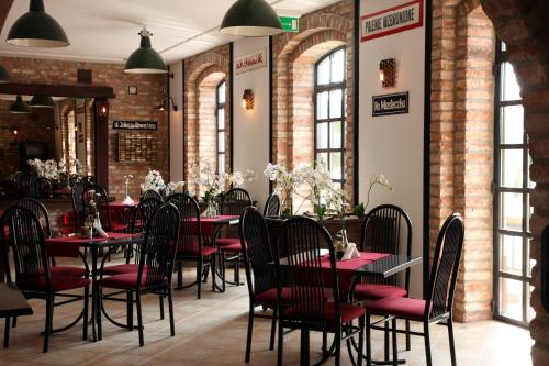 a restaurant with red tables and chairs and brick walls at Hotel Kameleon in Tarnobrzeg
