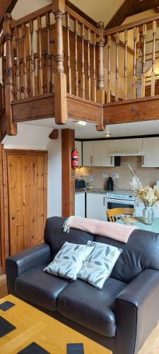 a black leather couch in a living room with a staircase at The Linhay in Teignmouth