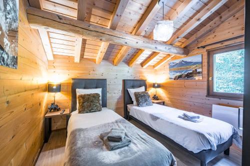 deux lits dans une chambre aux murs en bois dans l'établissement Chalet Soletoile - Grand Chalet 14p, au Chinaillon