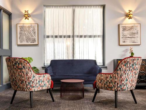 a living room with a blue couch and two chairs at The Harlow Hotel By AccorHotels in Harlow