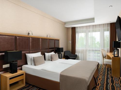 a hotel room with a large bed and a television at Aquaticum Debrecen Termal & Wellness Hotel in Debrecen
