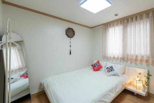 a bedroom with a white bed and windows at Metro Stay Daejeon Cozy home at transport hub in Daejeon