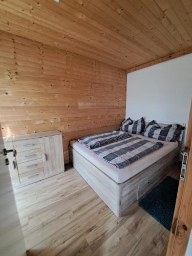 Un dormitorio con una cama en una habitación de madera. en Domeček Sára, en Mohelnice
