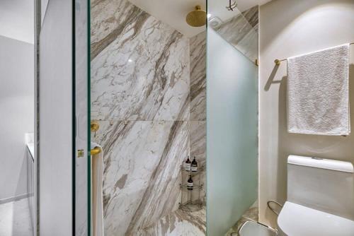 a bathroom with a toilet and a marble wall at Amazing Condo - Beach Access - Spa - Pool in Higuera Blanca