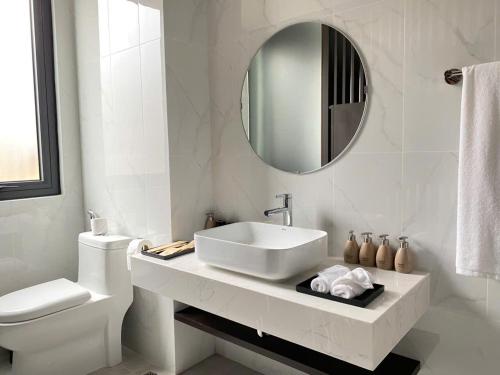 a white bathroom with a sink and a mirror at Căn hộ khách sạn wyndham Thanh Thuỷ in La Phu