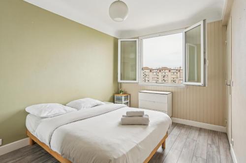Un dormitorio con una gran cama blanca con ventana. en Chic and comfortable apart near Paris, en Bagneux