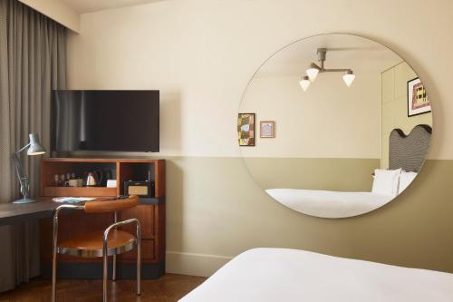 1 dormitorio con espejo, 1 cama y 1 silla en The Hoxton, Shoreditch, en Londres