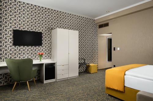 ein Hotelzimmer mit einem Bett und einem Fernseher an der Wand in der Unterkunft Hotel Allora in Budapest