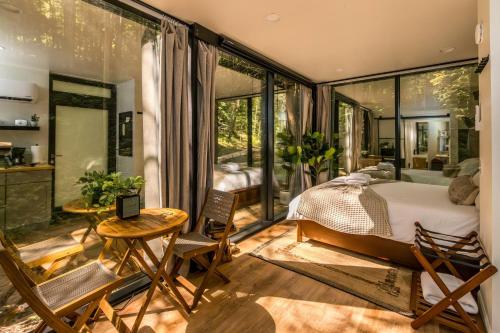 a bedroom with a bed in a room with large windows at Modern Mirror Home w/ Hot-tub | “Glass House” #2 in High Falls